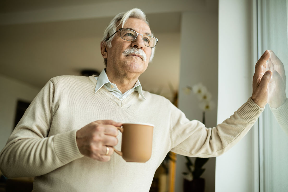 low-angle-view-senior-man-day-dreaming-while-drinking-coffee-looking-through-window